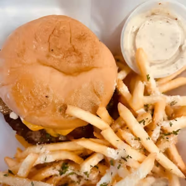 A cheeseburger with a side of seasoned fries and a dipping sauce from Burgers & Brats.