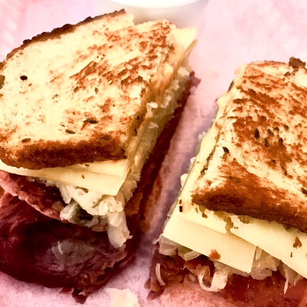 Close-up of a Reuben sandwich cut in half, showing corned beef, sauerkraut, and cheese.